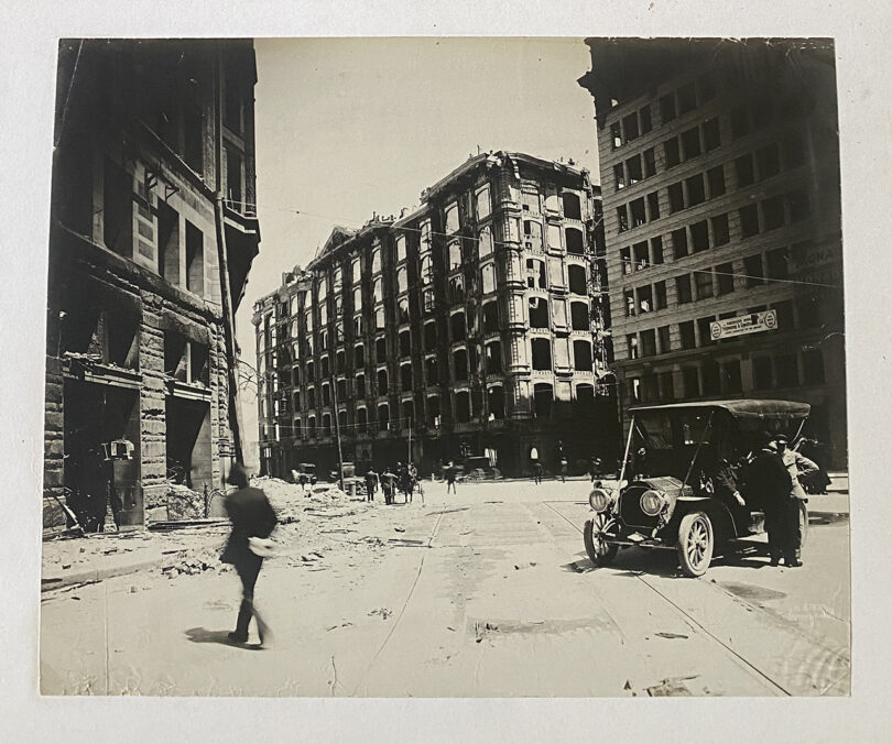 old black and white photo of someone walking down a dirty city street