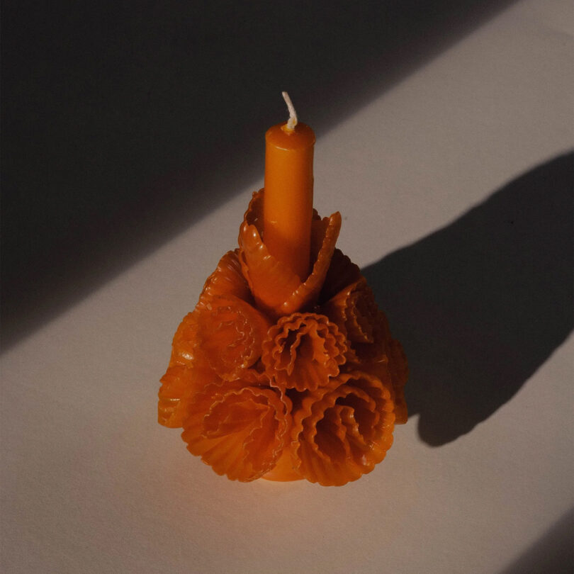 dark orange candle adorned by wax flowers