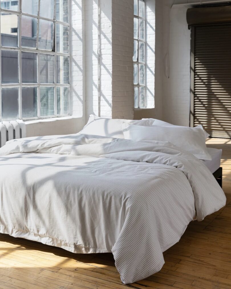 Kotn Bedding showcased on a bed in a sunlit, industrial-like room