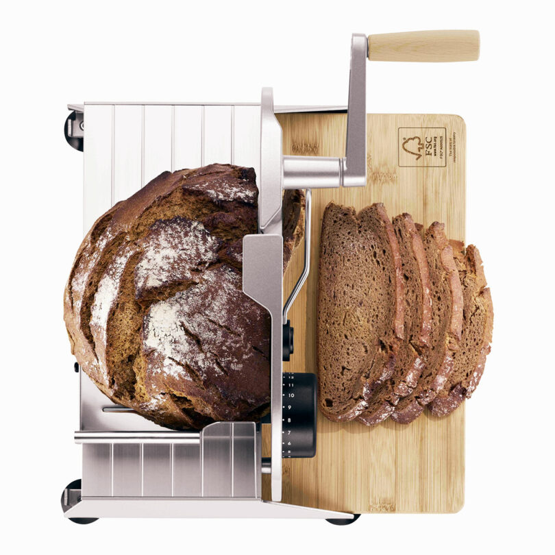 down view of food slicer with round loaf of pumpernickel bread being sliced