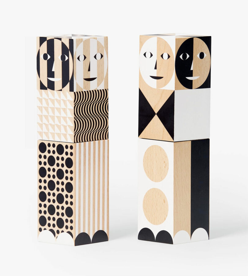 two angled black, white, and wood salt and pepper grinders with shapes and faces on them