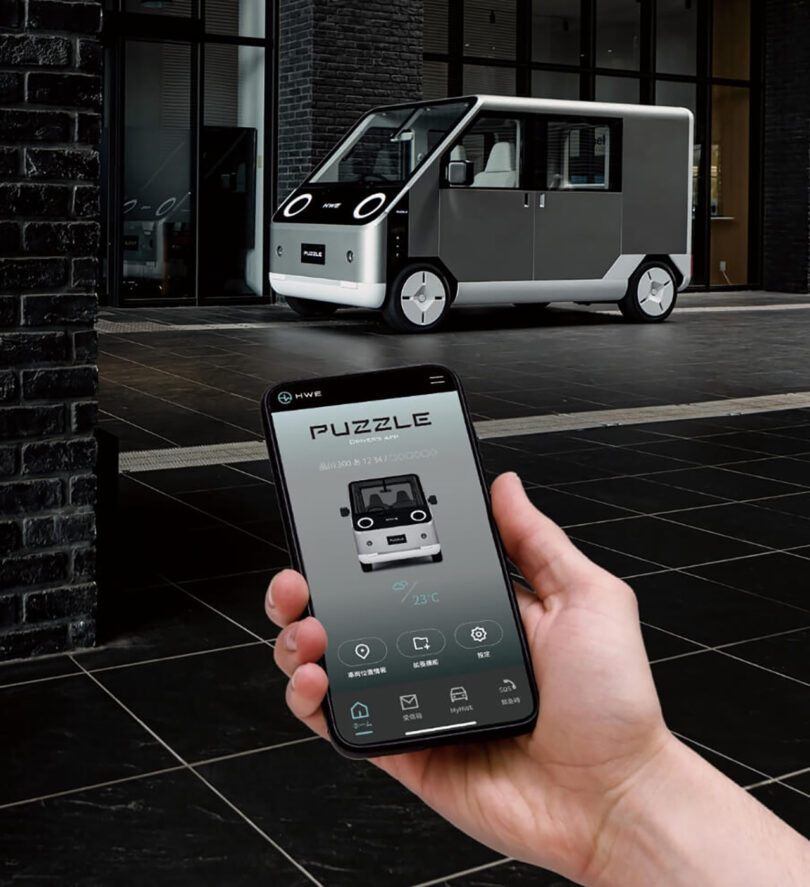 Hand holding smartphone shown with MyHWE app and Puzzle EV van in the background.