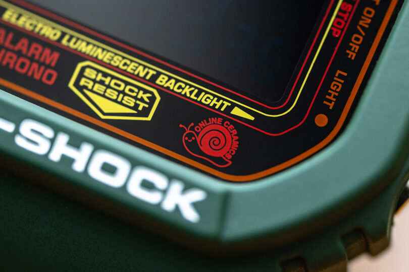 Small red snail Online Ceramics logo in bottom right hand corner of the special edition G-SHOCK digital wristwatch.