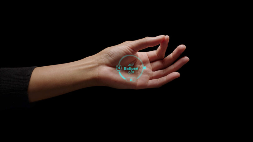 Open palm with two pinched fingers and a green laser ink screen projected on it showing how to make a selection using gestures using the Humane AI pin.