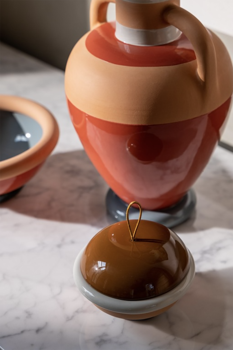 deep orange and light brown ceramic vase, bowl, and cup on a wood surface