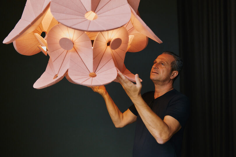 light-skinned man examining a pink felt acoustic chandelier