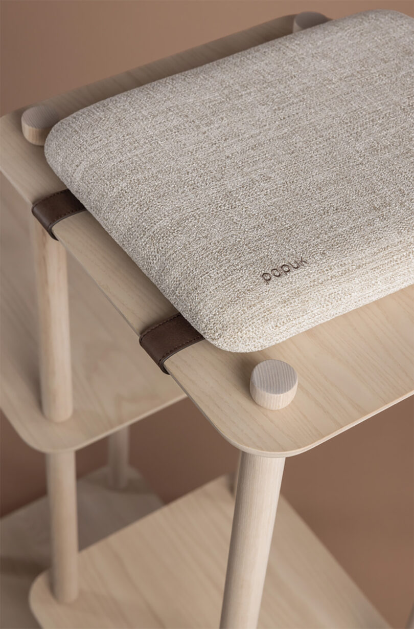 Detail of Connect cat tree platforms cushion and wood dowel constructions et against a beige-tan backdrop.
