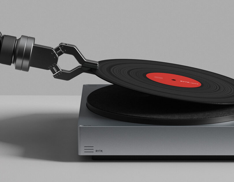 Robotic arm holding and placing a vinyl record onto the RYTM turntable platter.