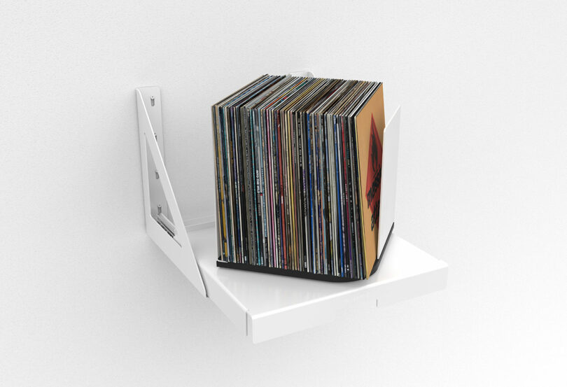 angled view white wall-mounted pull out shelf that holds and rotates stored vinyl records