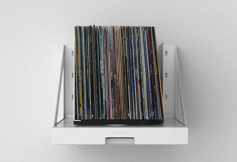front view of white wall-mounted pull out shelf that holds and rotates stored vinyl records