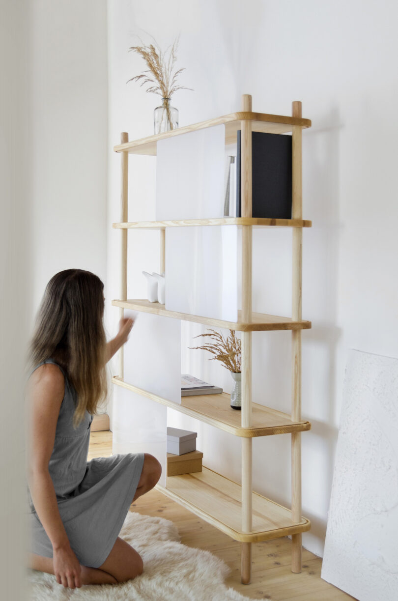 woman adjusting transparent panel on wooden shelf