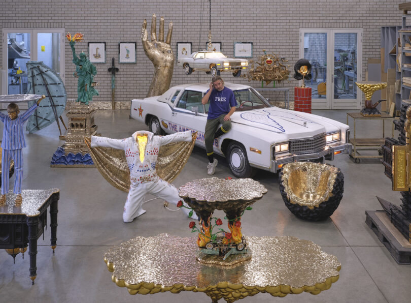 man sitting on white car in a room of sculptures and furnishings