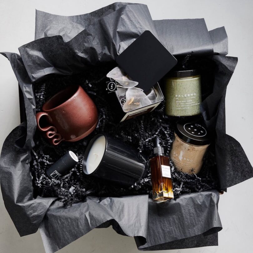 gift set with various wellness products inside a box with grey tissue paper