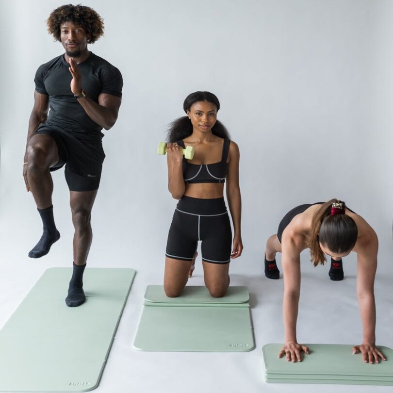 a man and two women working out on green yoga mats