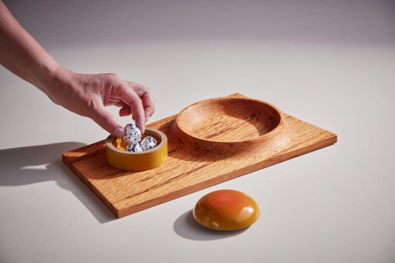 hand lifting candy off of tray with integrated bowl with lid and plate