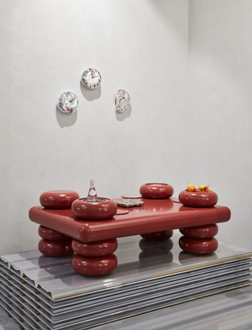 red table next to clock sculptures on wall