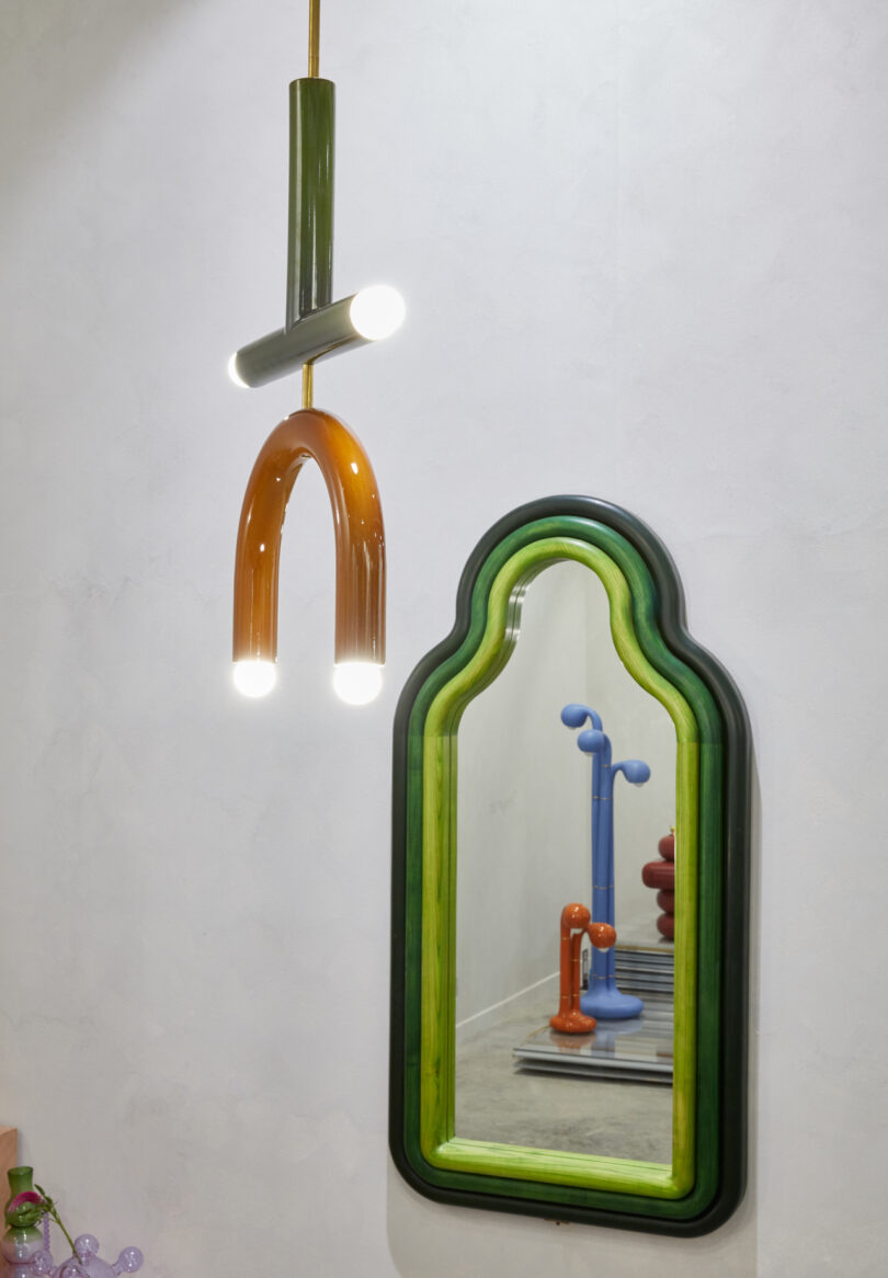 green mirror next to sculptural pendant light