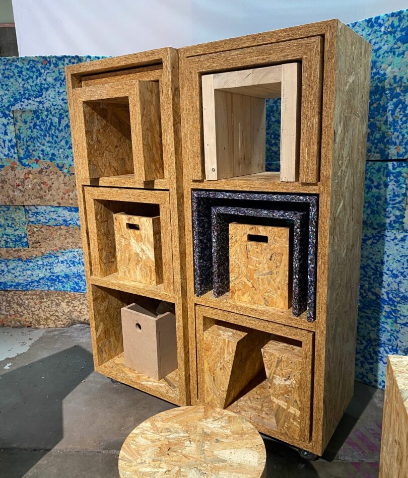 A set of two tall OSB rectangular boxes with shelves forming cubes, with tables and boxes stacked inside each other inside each cube