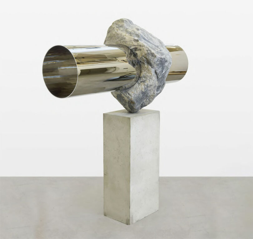 Metal tube-like scuplture on concrete base in gallery