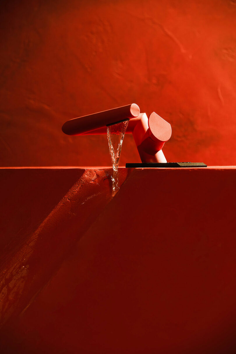 angular red faucet with water flowing into red vessel
