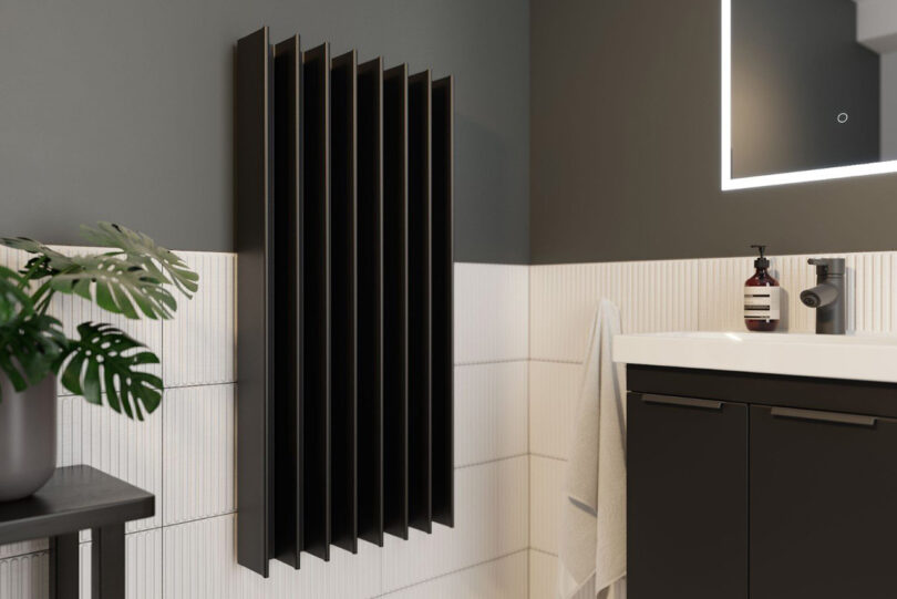 Modern bathroom with black vertical Gordon Double electric towel drying rail mounted on the right side near small sink basin.