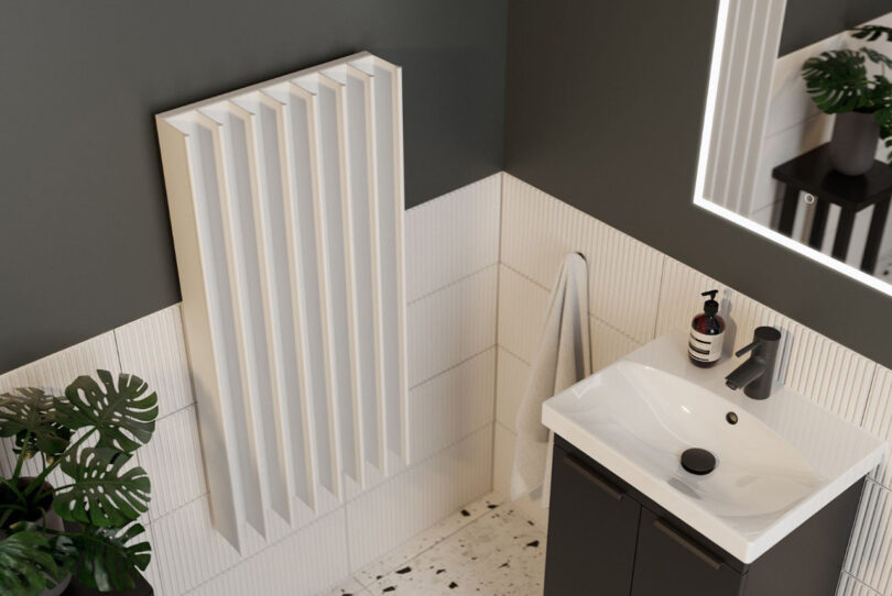 Modern bathroom with white vertical Gordon Double electric towel drying rail mounted on the right side near small sink basin.