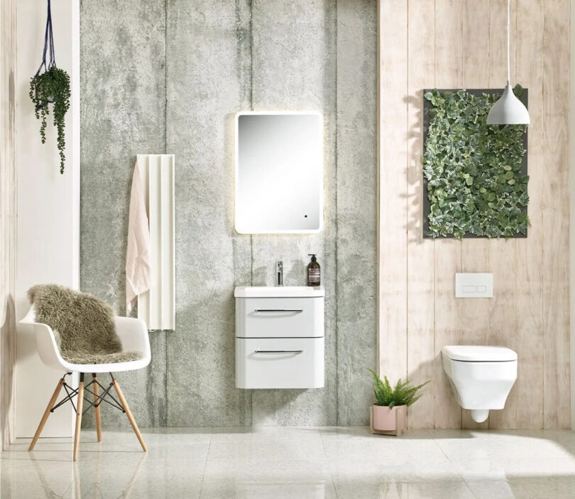 Modern bathroom with white vertical Gordon electric towel drying rail mounted to the left of a small floating sink in the middle with mirror overhead and wall mounted toilet to the far right.