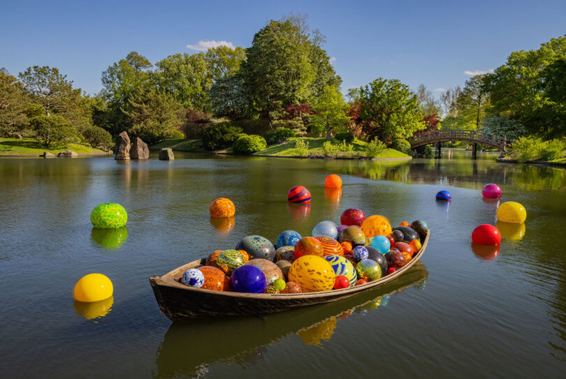 a boat in a lake filled with various sizes and colors of glass globes