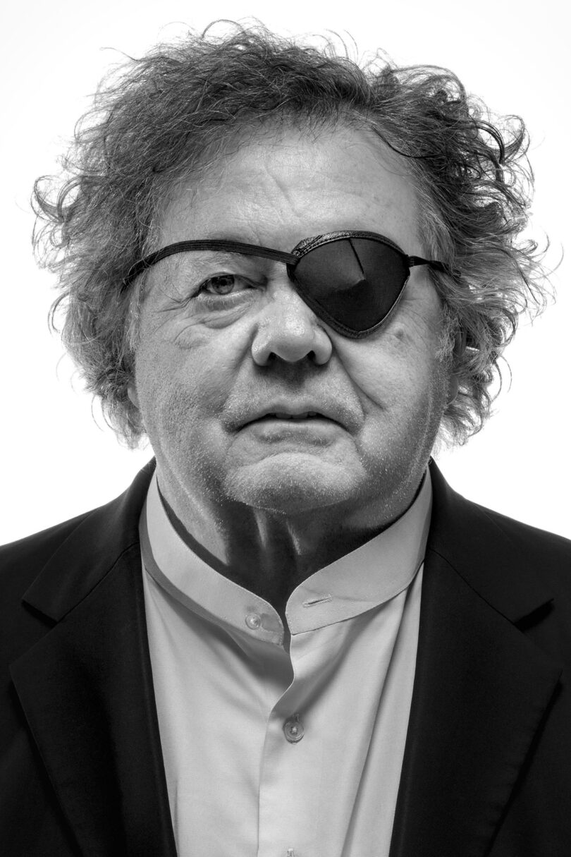 black and white image of a light-skinned man with an eye patch looking at the camera