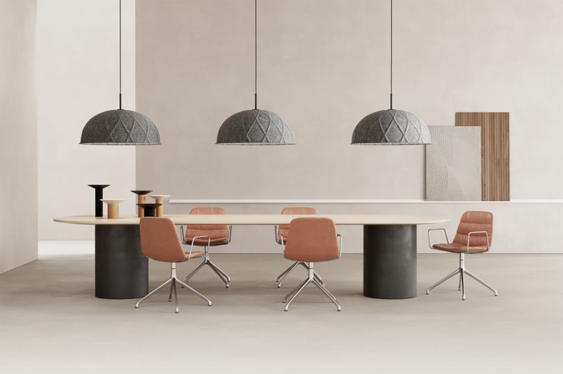 three half-dome grey pendant lights hang over a large modern conference table and swivel chairs