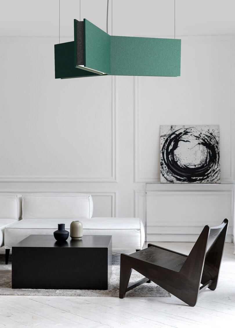 green geometric pendant light hangs over a styled living space