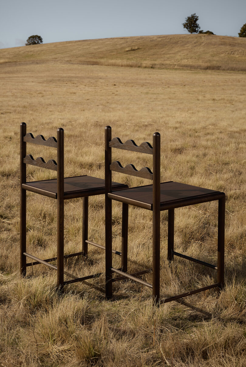 two tall dark wood stools in an off-season field