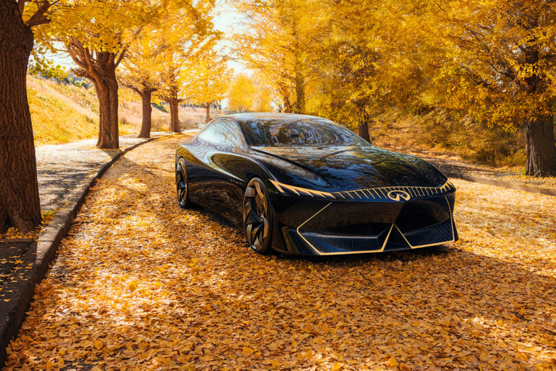 All-electric Vision Qe fastback sedan parked in a golden autumn hued setting of trees.