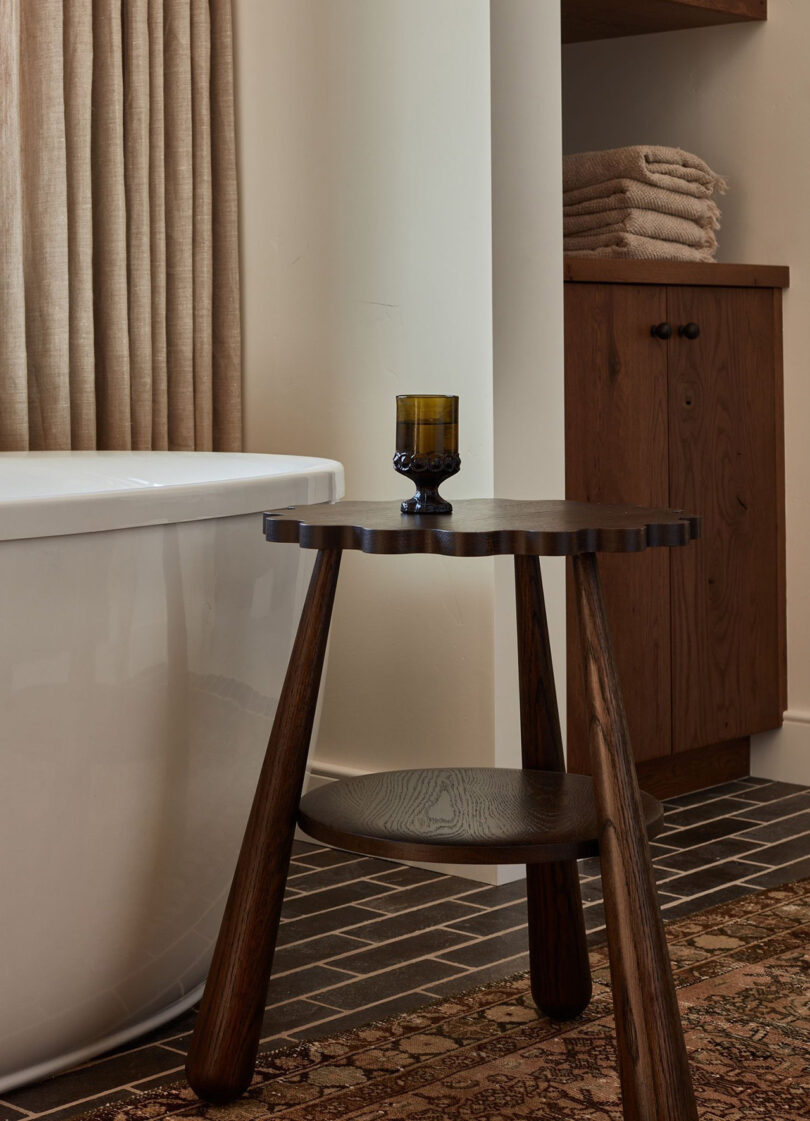 dark wood tripod stool holding a glass