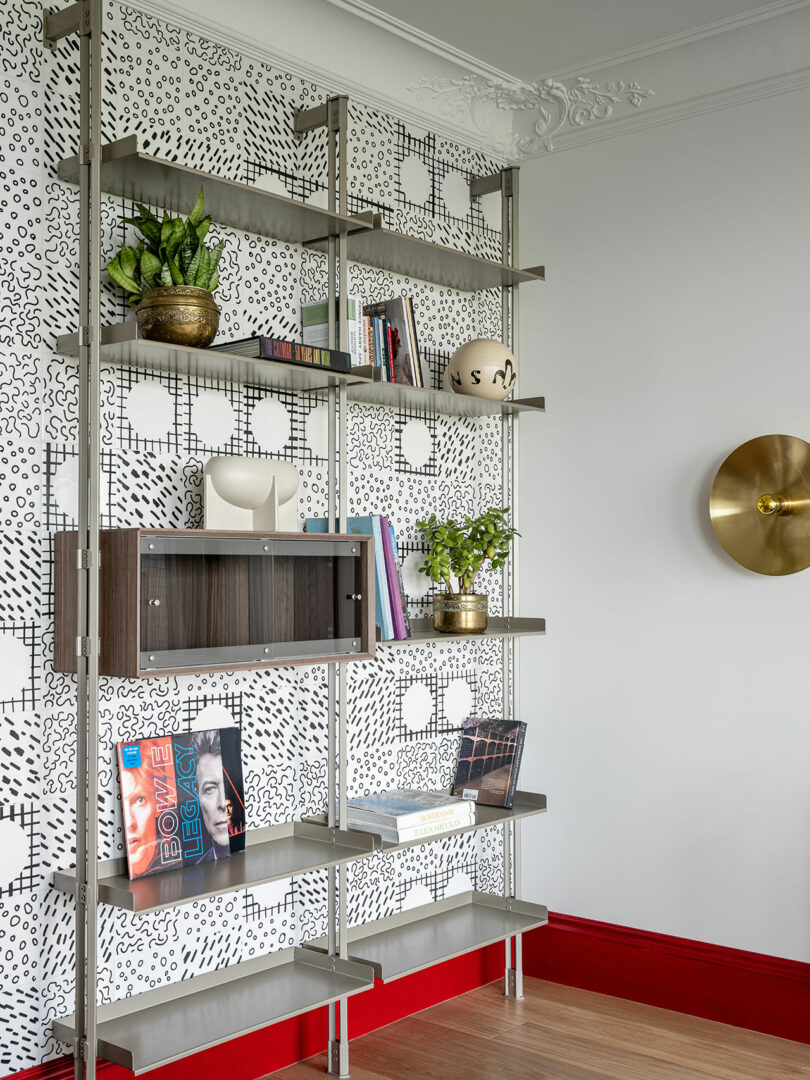 angled view of chrome wall-mounted bookshelf filled with random objects and plants