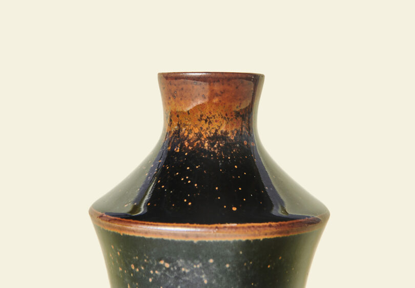 Detail of ceramic sake vessel with dark speckled and glossy glaze along edges.