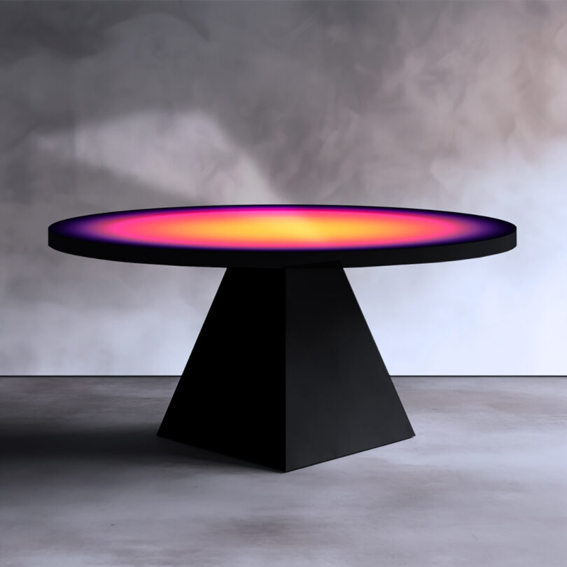 black table with black pyramid-shaped base and round top with radial color