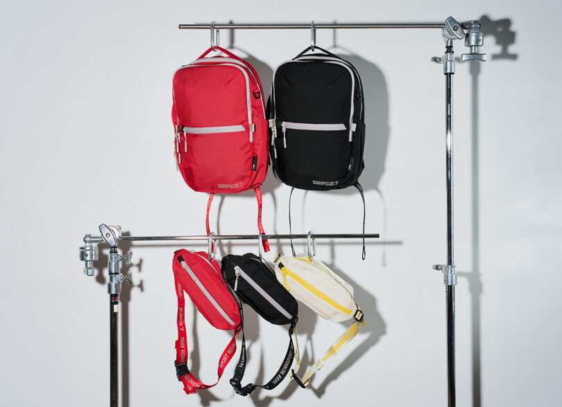 Entire Aer x Porsche Rennsport Reunion 7 backpacks and slings collection displayed hanging on metal racks.