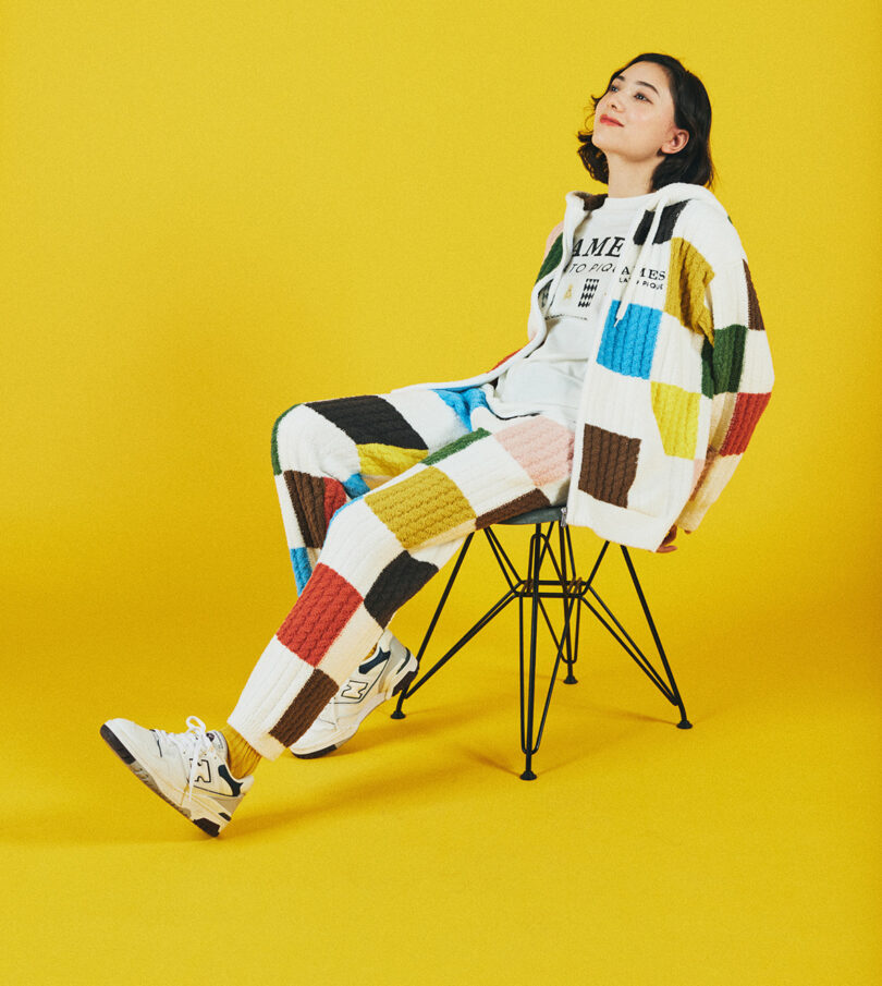 woman lounged back sitting on chair with checkered loungewear on yellow background