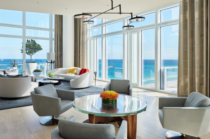 styled interior space overlooking the ocean with floor to ceiling windows and plenty of seating