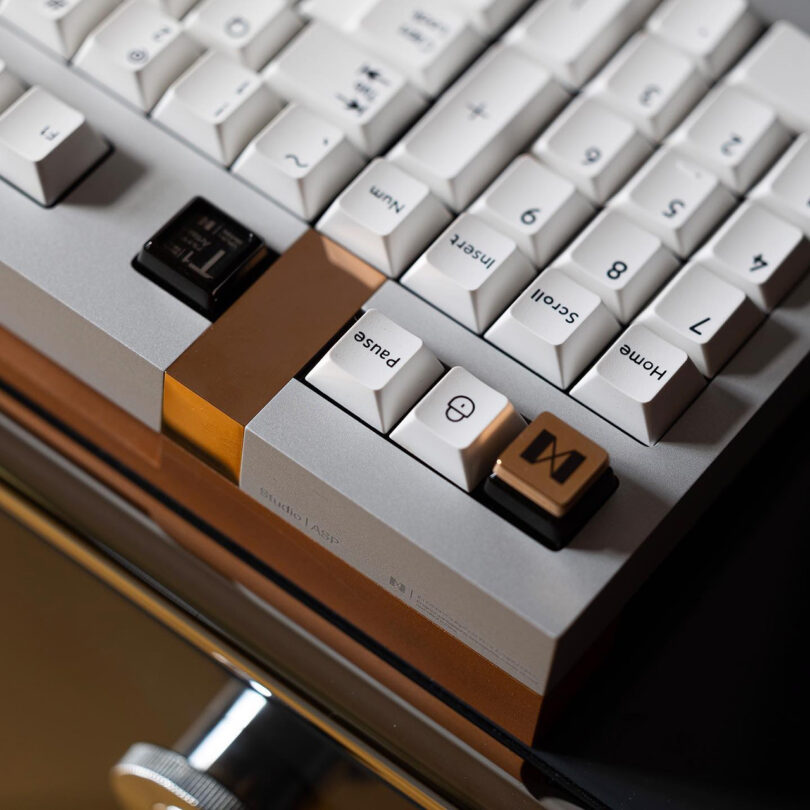 Close up corner view of geistmaschine mechanical keyboard in white and bronze focused upon numerical keys section.