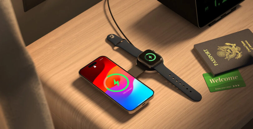 ButterFly MagSafe charger shown on wood side table recharging Apple iPhone 15 and Apple Watch at the same time, with a passport book, alarm clock and hotel key to the right.