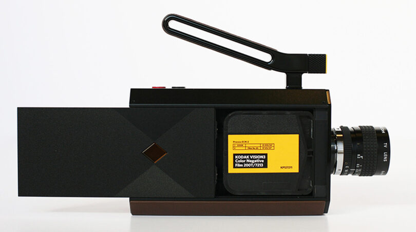 New Kodak Super 8 hybrid video camera from side profile with its film bay door open showing Kodak Vision Color Negative Film cartridge inside with yellow label.