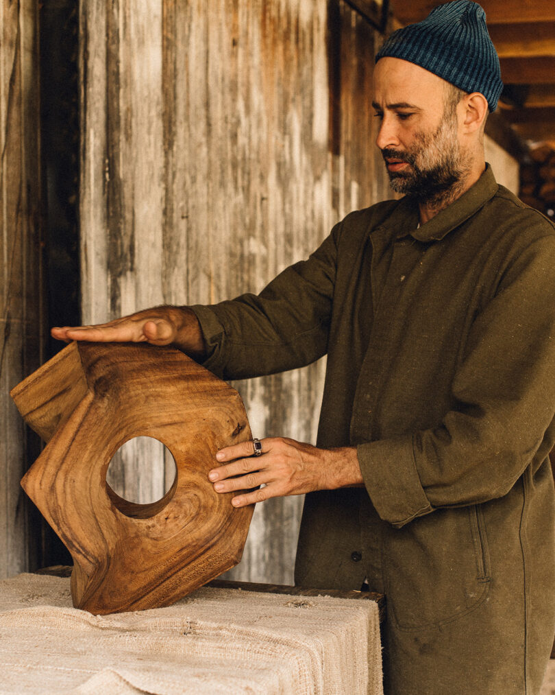  Artist Aleph Geddis with his hands over one of his wood carved geometric sculptures.