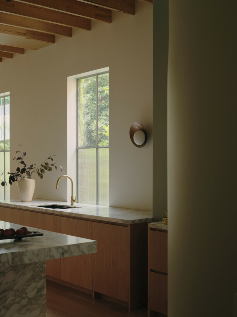 A serene kitchen space with warm wooden cabinetry topped with a marble countertop