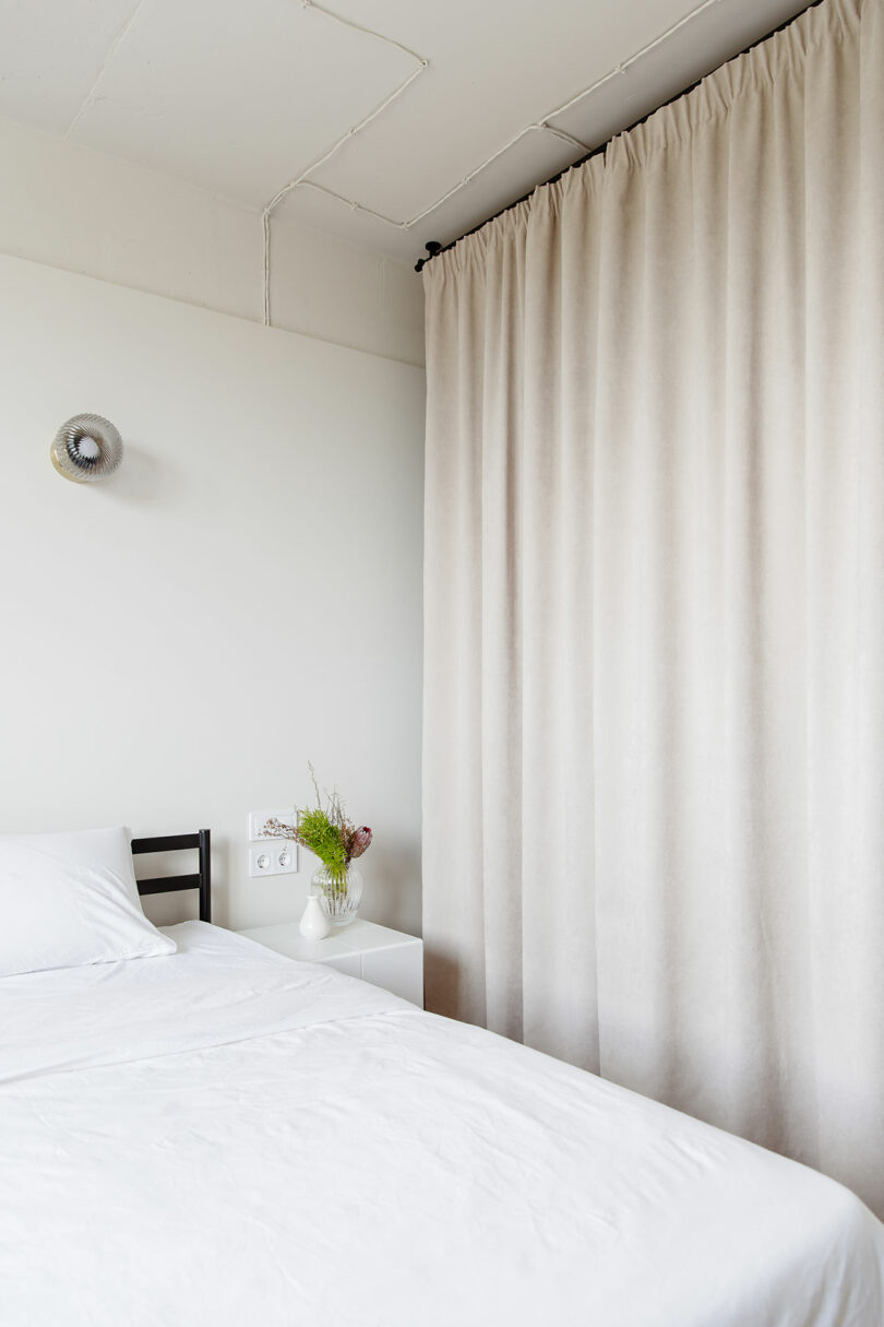 angled position of minimalist achromatic chamber pinch achromatic bedding and achromatic hanging curtain