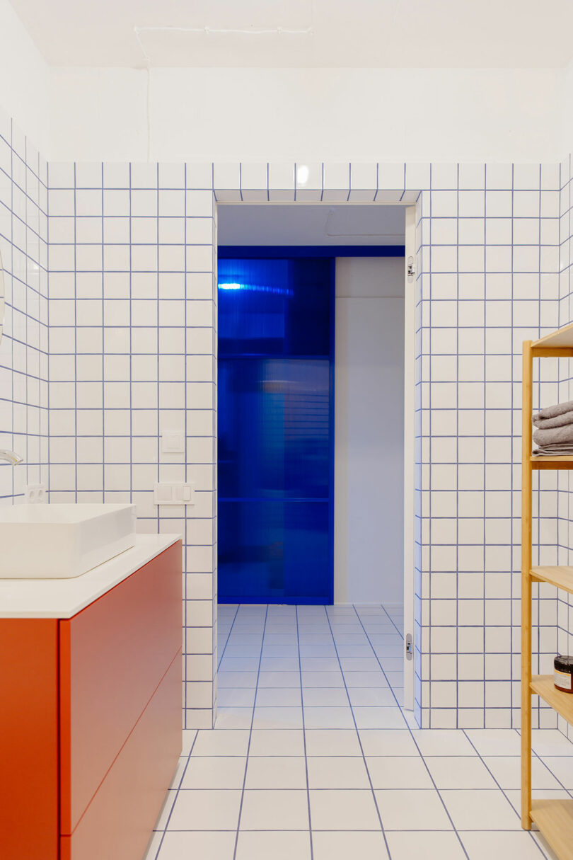 interior changeable of modern bath pinch achromatic grid tile, reddish sink, yellowish shelf, looking into hallway