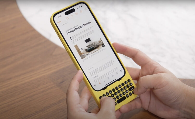 Person holding iPhone inside yellow Clicks iPhone case with "Interior Design Trends" story on screen