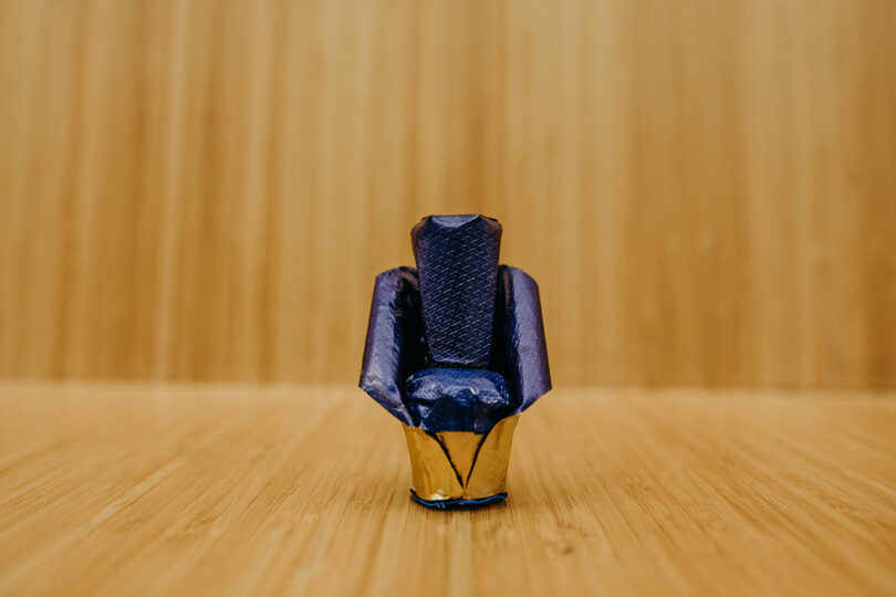 A miniature chair model made out of champagne bottle packaging against a bamboo backdrop.