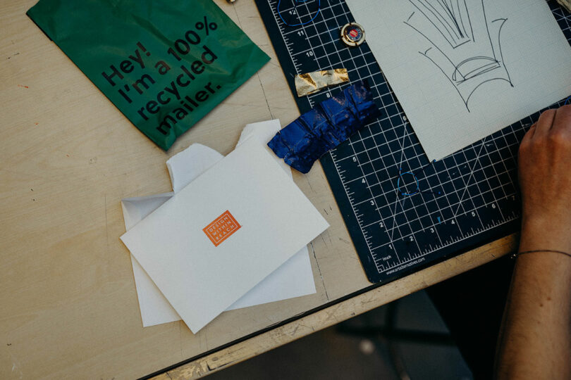 A note, some packaging, and a cutting mat on the top of a studio table